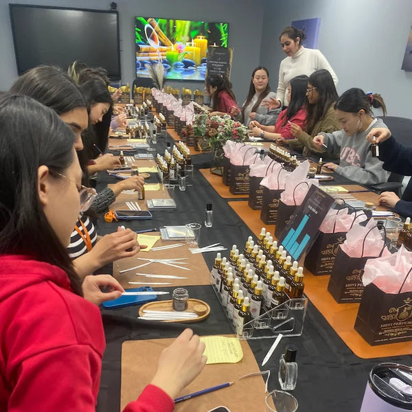 Group of people at a table for perfume with various items including bottles and perfumes. create your own perfume