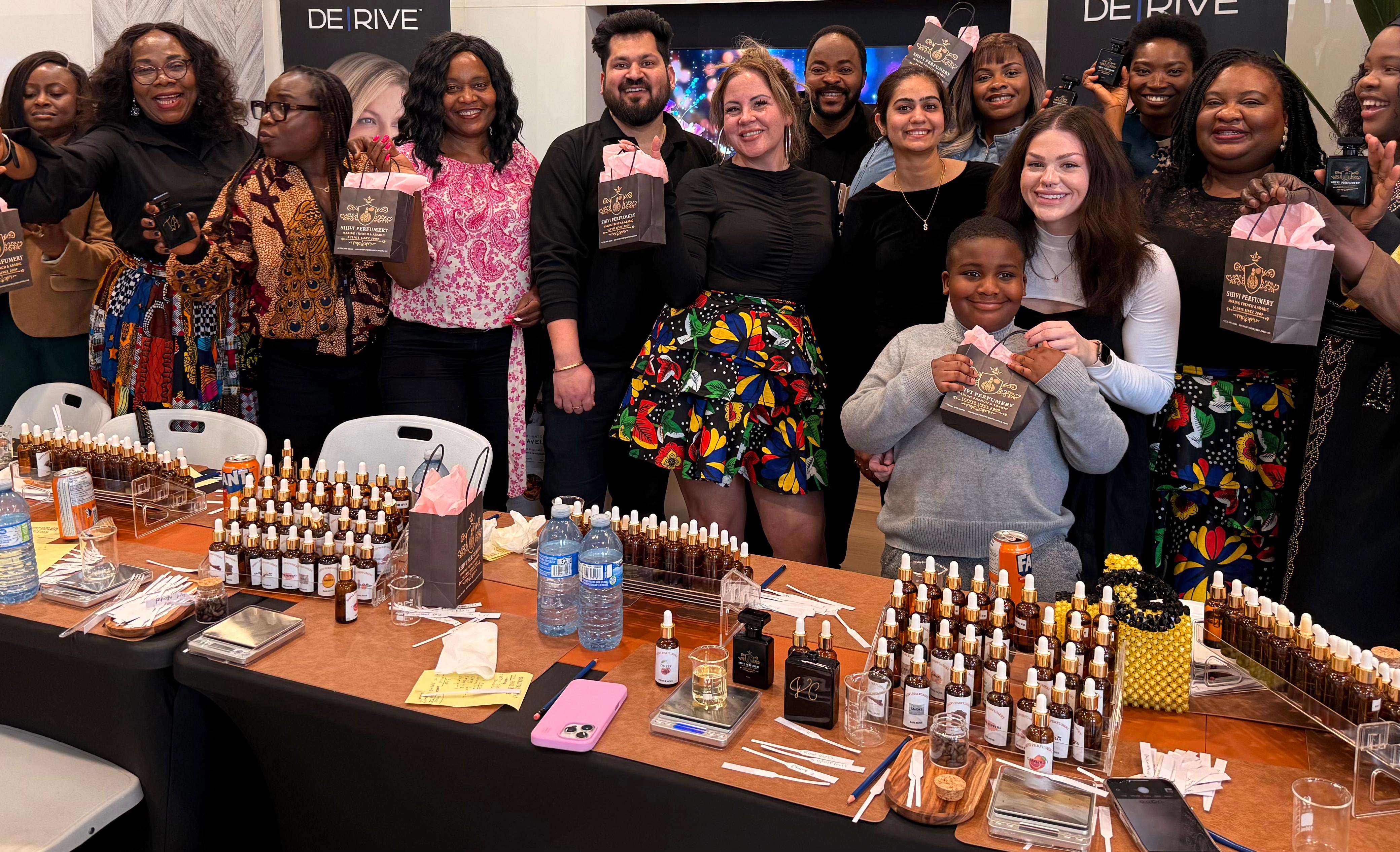 Group of people at a table with various bottles and products, likely at an perfume party bar